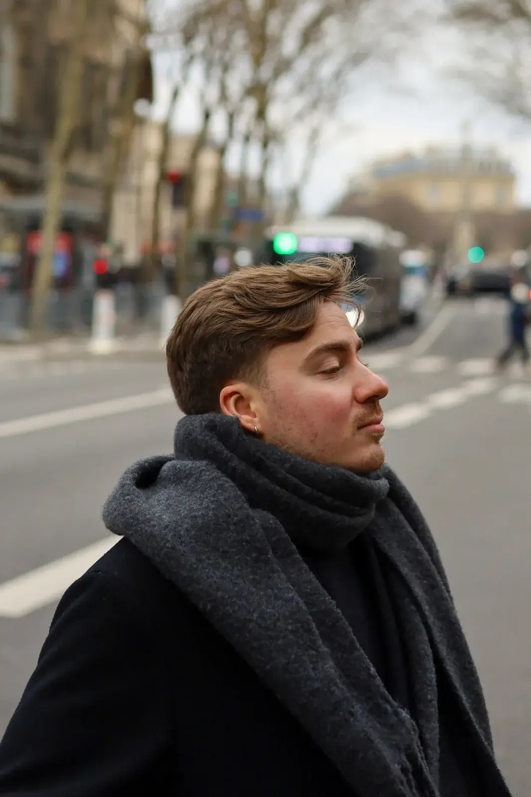 Victor Basov wearing a dark coat and scarf on a city street